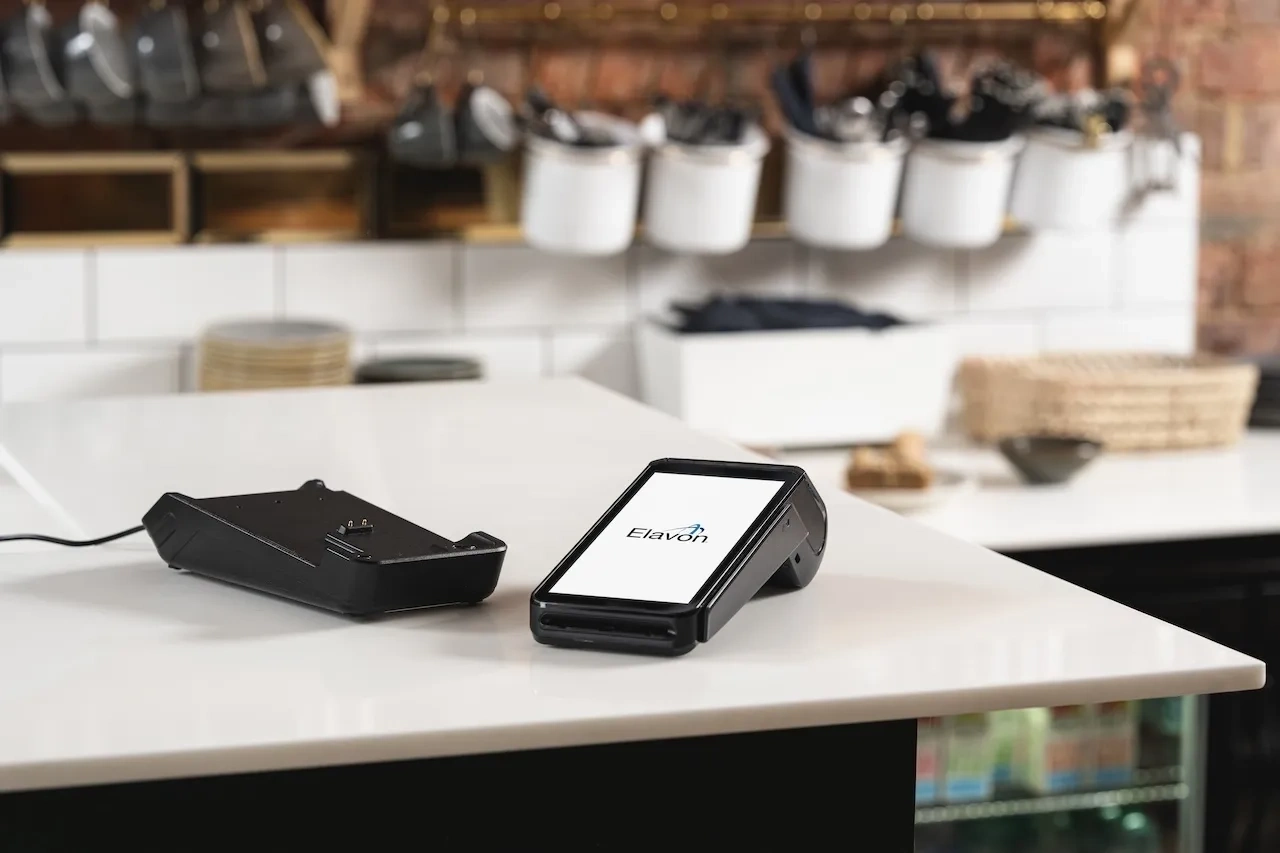 Elavon pos terminal auf theke im café mit küchenutensilien im hintergrundv