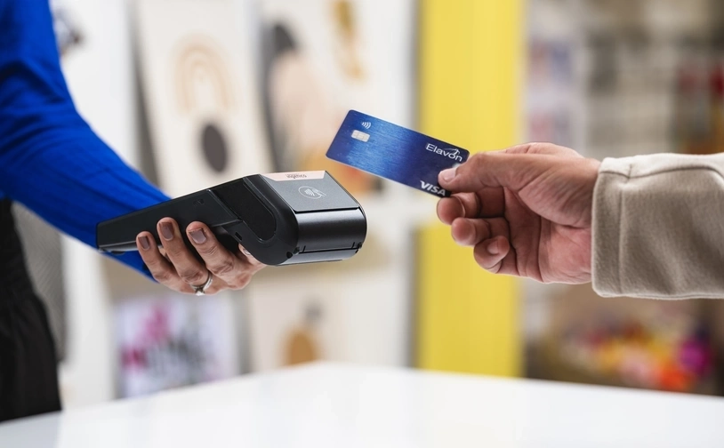 Draufsicht auf ein portables zahlungsterminal auf einem holztisch mit kerzen verpackungen und einer schürze