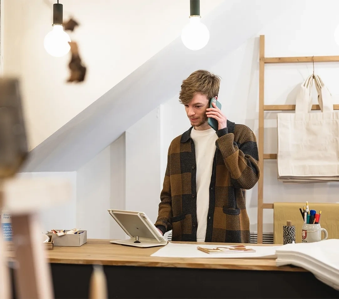 kleinunternehmer arbeitet an einem laptop an einem holztisch mit einem notizbuch und einer tasse kaffee